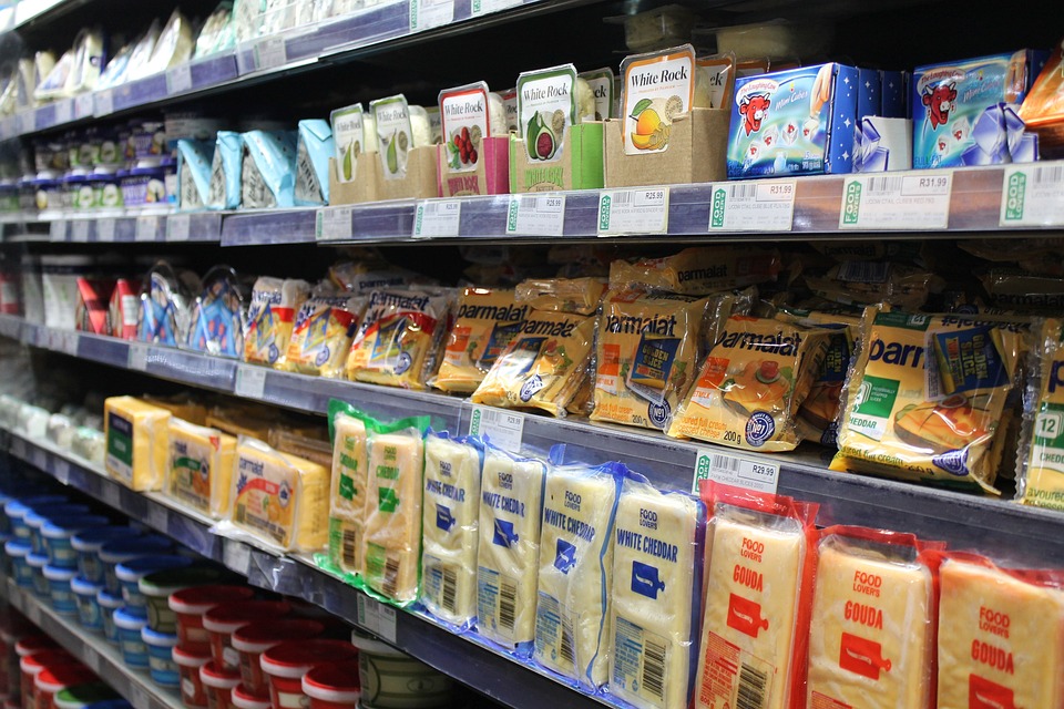 Different cheeses lined up in an open commercial refrigerator