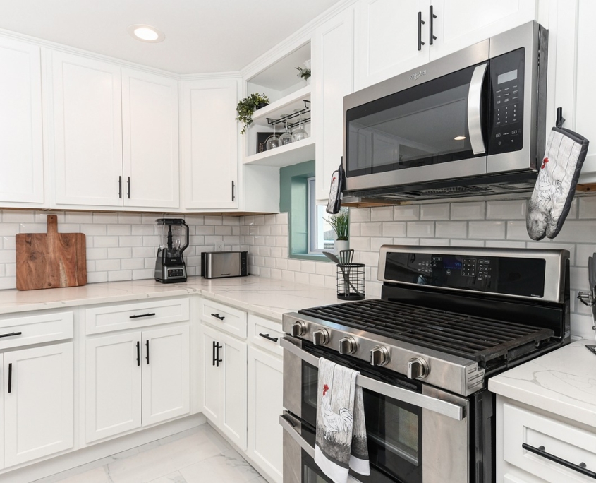 A picture of a white kitchen with a stainless steel microwave