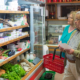 An older couple looking at food in a commercial refrigerator in a grocery store
